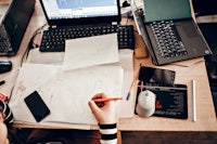 a person working at a desk with a laptop and a pen