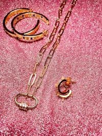 a set of gold jewelry on a pink cloth