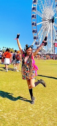 a girl posing in front of a ferris wheel