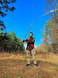 a man standing in a field with a bow and arrow